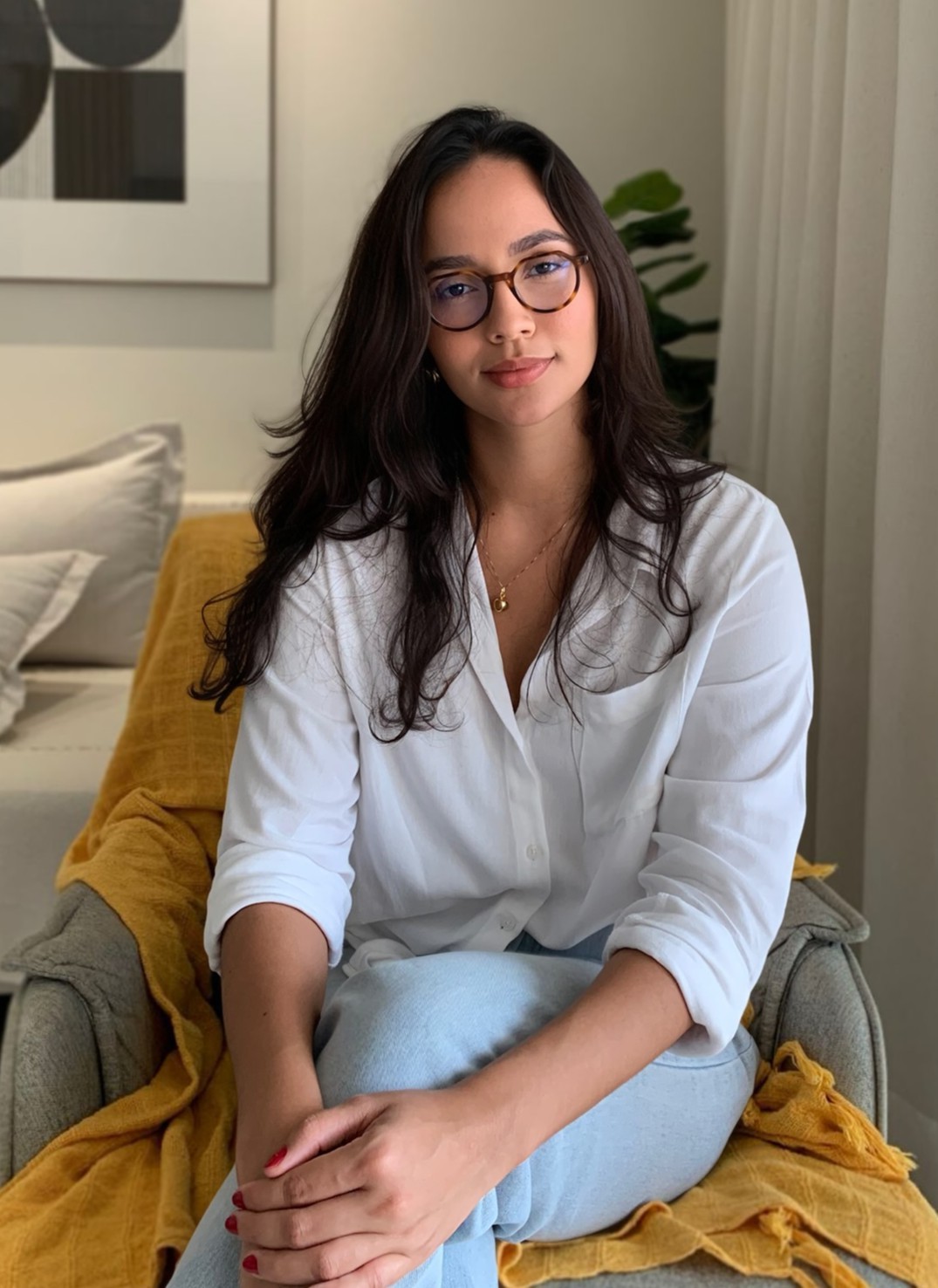 Flávia Guimarães sorrindo, com óculos na mão